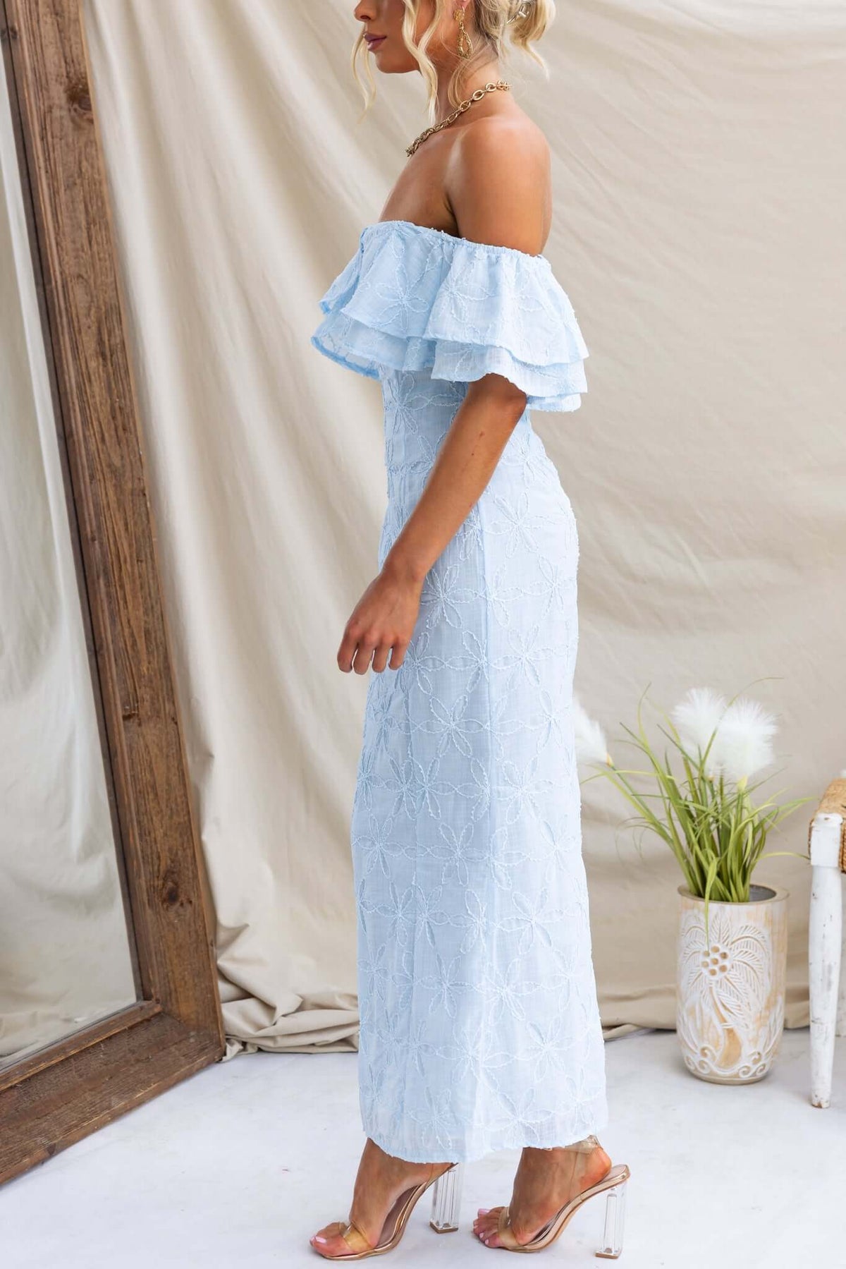 Light blue Jaqcues maxi dress with off-the-shoulder ruffles, showcasing textured material and a fitted silhouette.