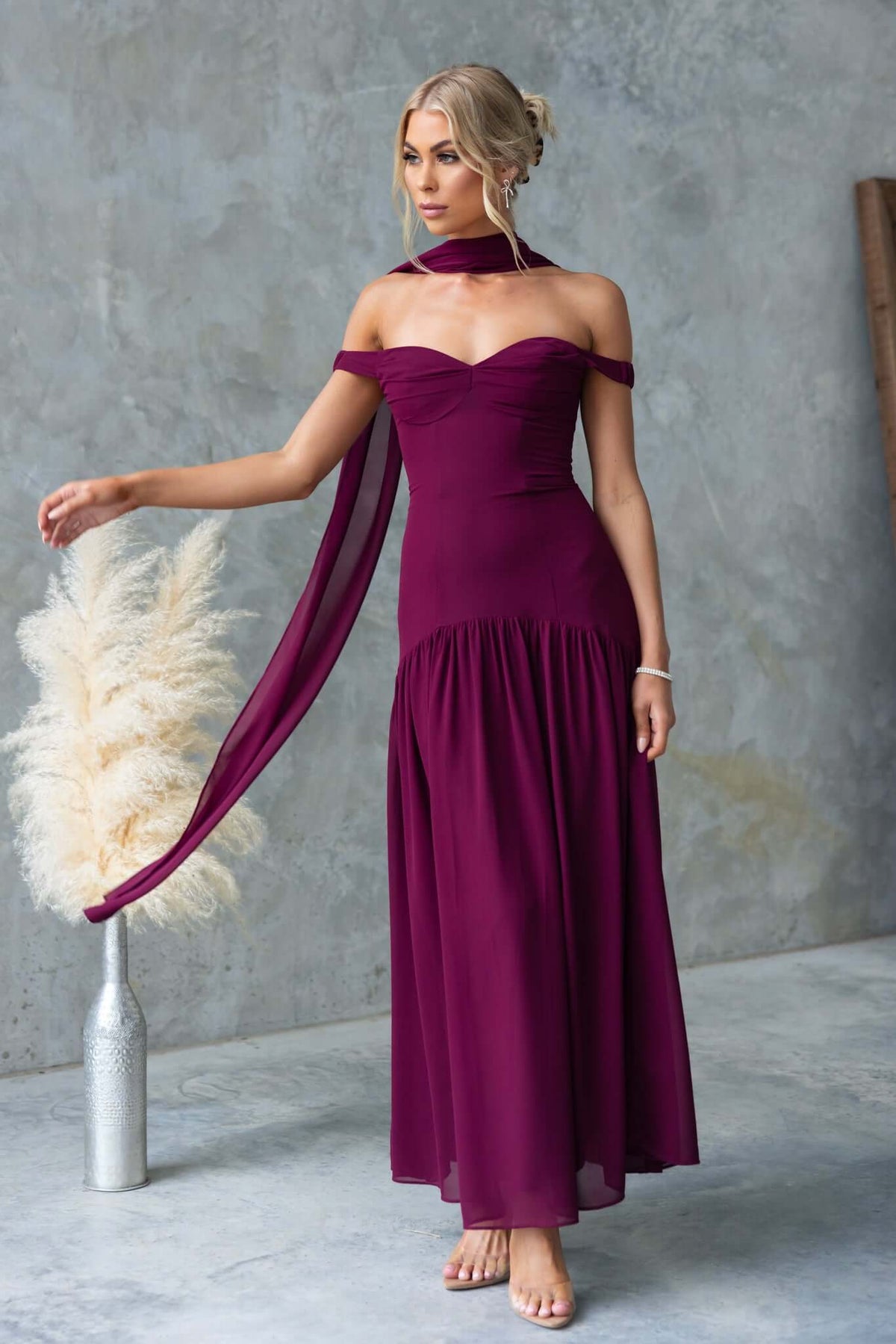 Elegant off-shoulder jazz maxi dress in burgundy with flowing skirt and removable tie detailing.