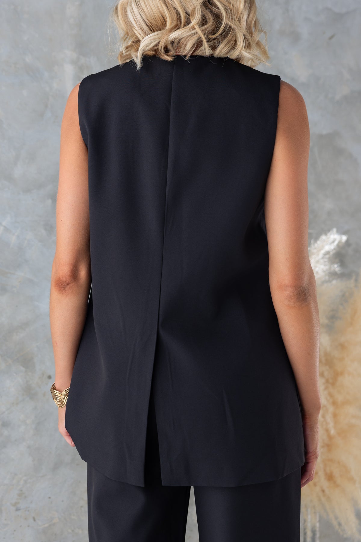Back view of Josefina Top featuring a vest style, split at back, in black with a sleek design.