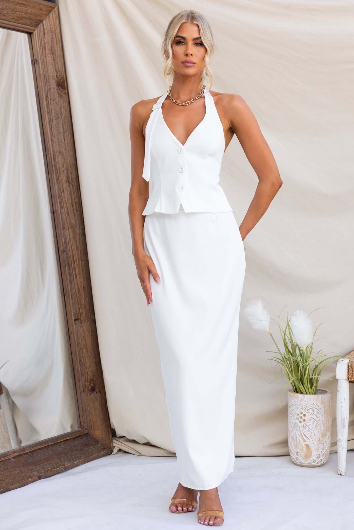 Stylish woman in white Julien Maxi Skirt paired with a halter neck top, featuring a mid-high waist and back split.
