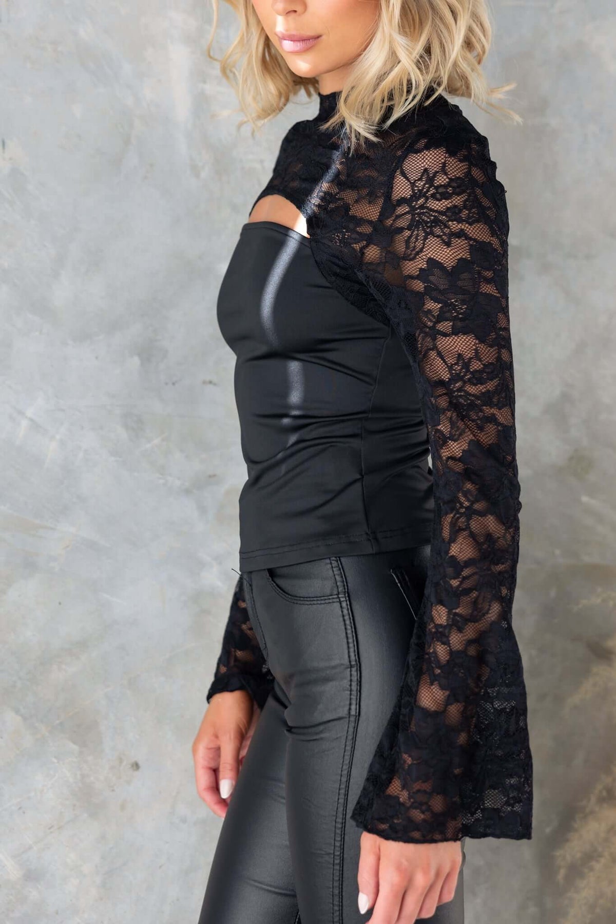 Stylish Kaiya Top featuring a mock neckline, lace panel, and cut-out bust, paired with sleek black bottoms.