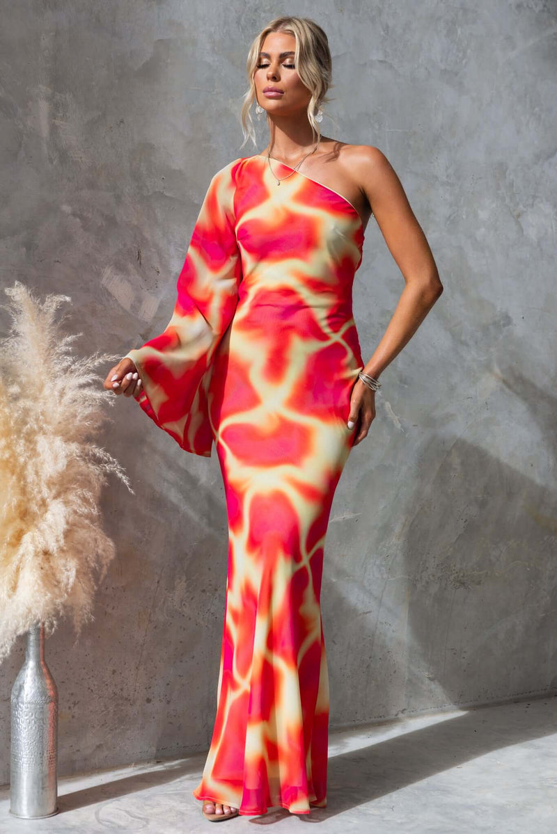 Model wearing the Kansai Maxi Dress, featuring a one-shoulder neckline and vibrant colors against a textured backdrop.