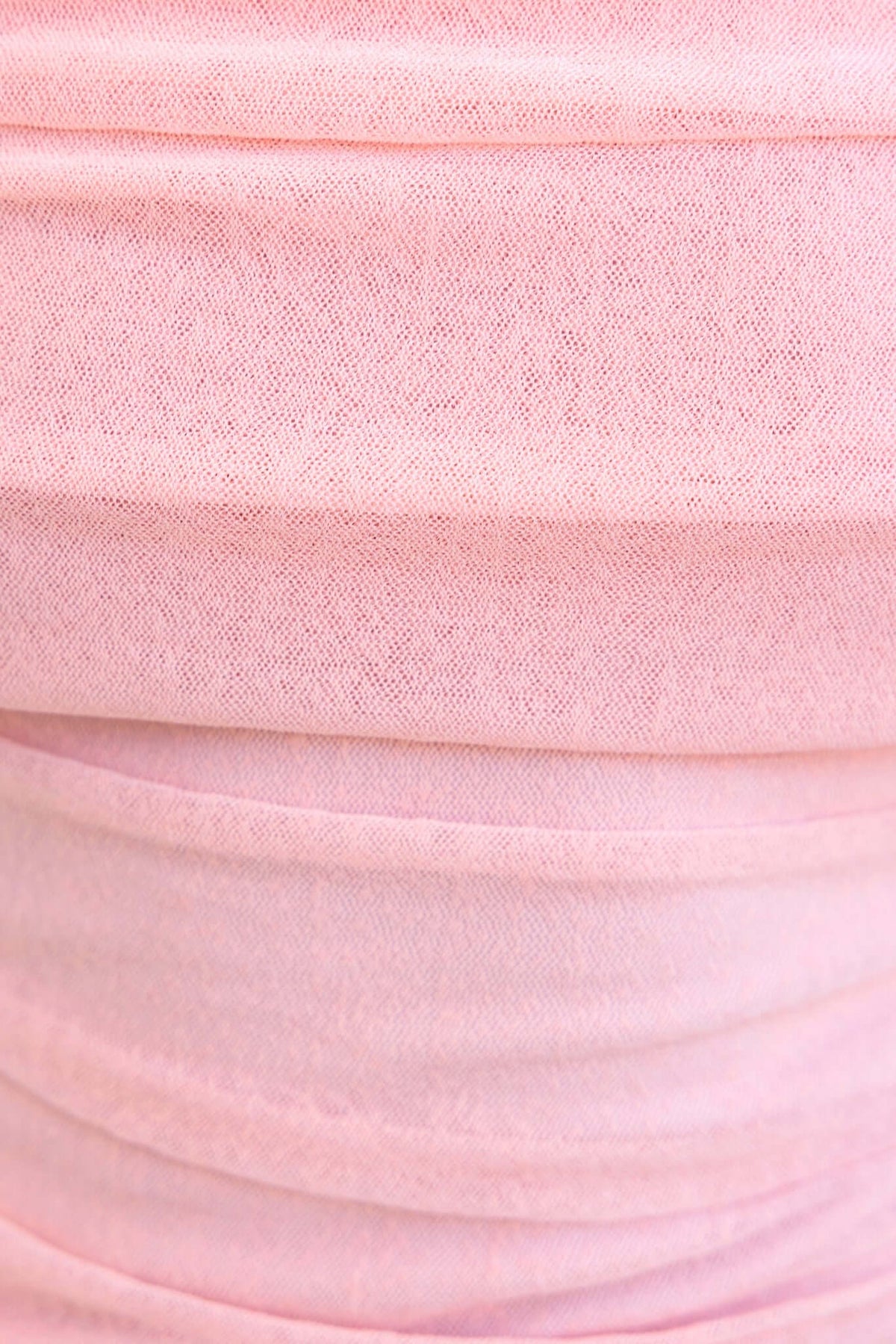Close-up of soft pink fabric with stretch, showcasing the texture and color of the Karmy Top.