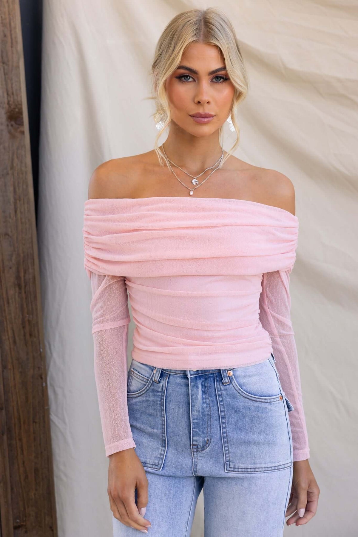 Karmy Top in soft pink featuring an off-shoulder neckline, stretch fabric, styled with light blue jeans.