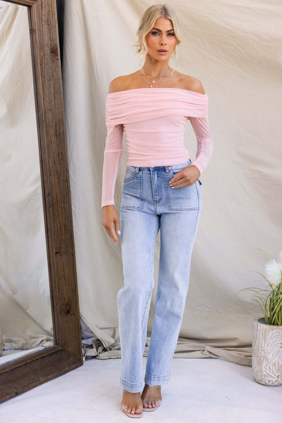 Karmy Top with off-shoulder neckline, styled with light blue jeans, showcasing stretchy material in soft pink.