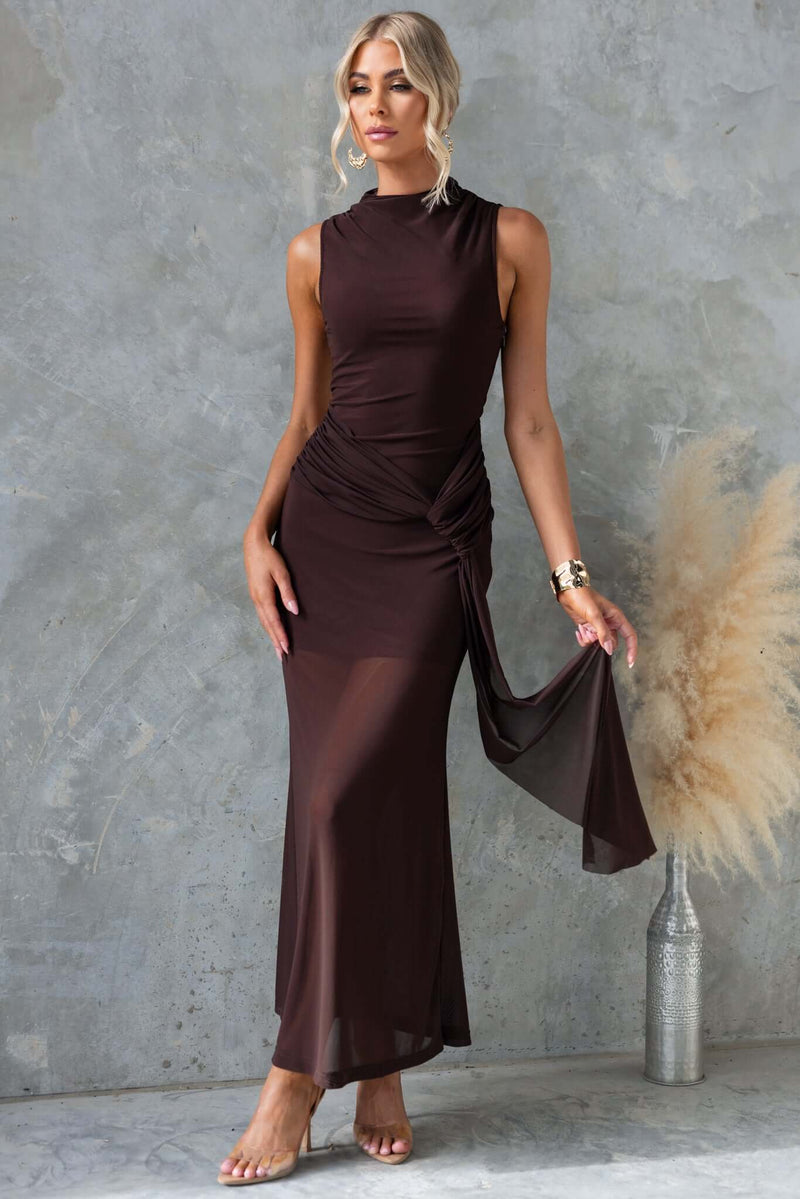 Karter Maxi Dress in dark brown with high neckline, draping material at waist, and mesh details, styled for elegance.