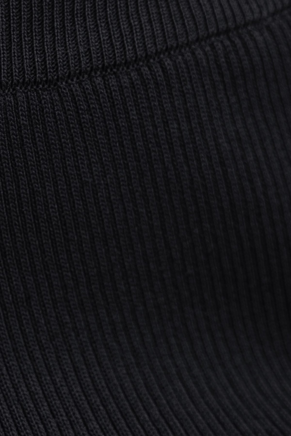 Close-up of Keene Pants showing mid-high waist elastic waistband and knit ribbed texture in black fabric.