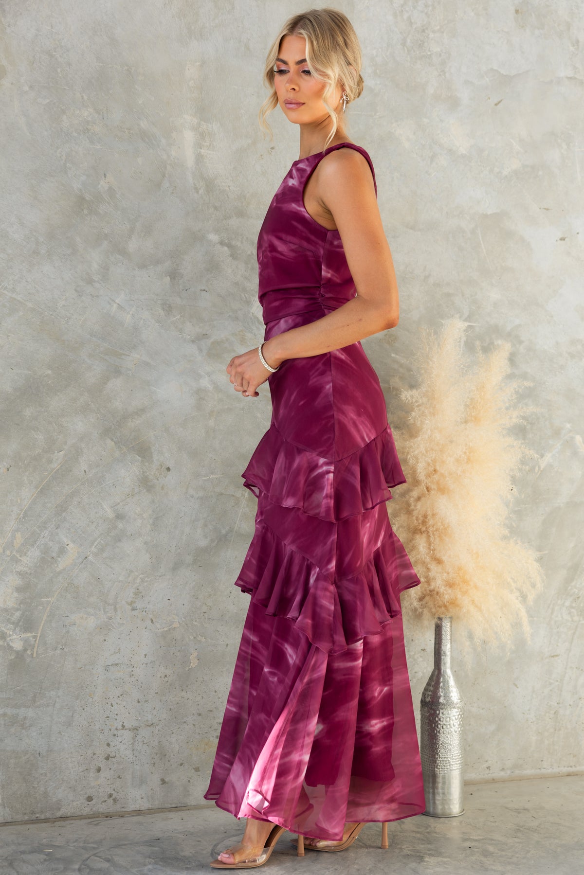 Kilian Maxi Dress in burgundy with high neckline and tiered ruffles, styled elegantly against a textured background.
