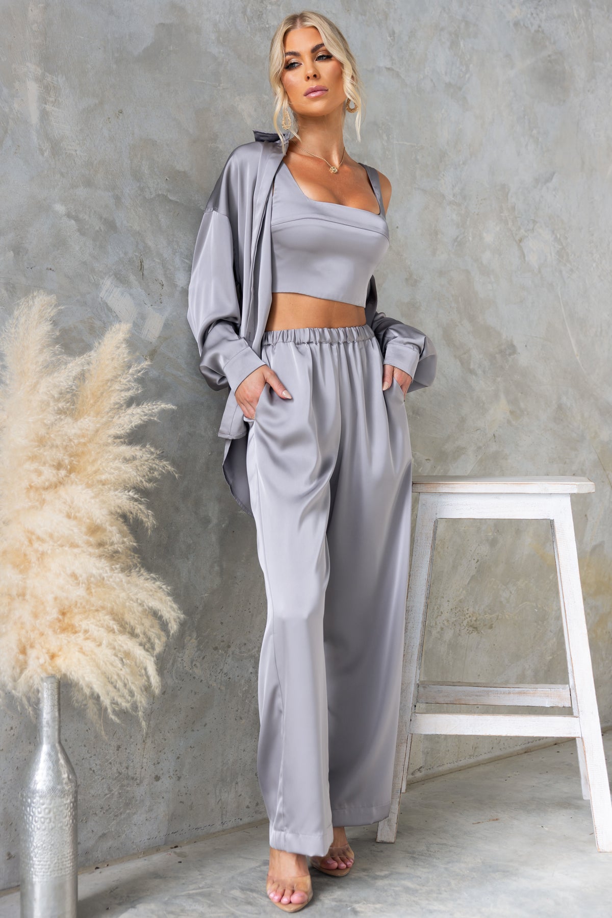 Model wearing a stylish light gray satin two-piece set featuring a cropped top and relaxed pants.