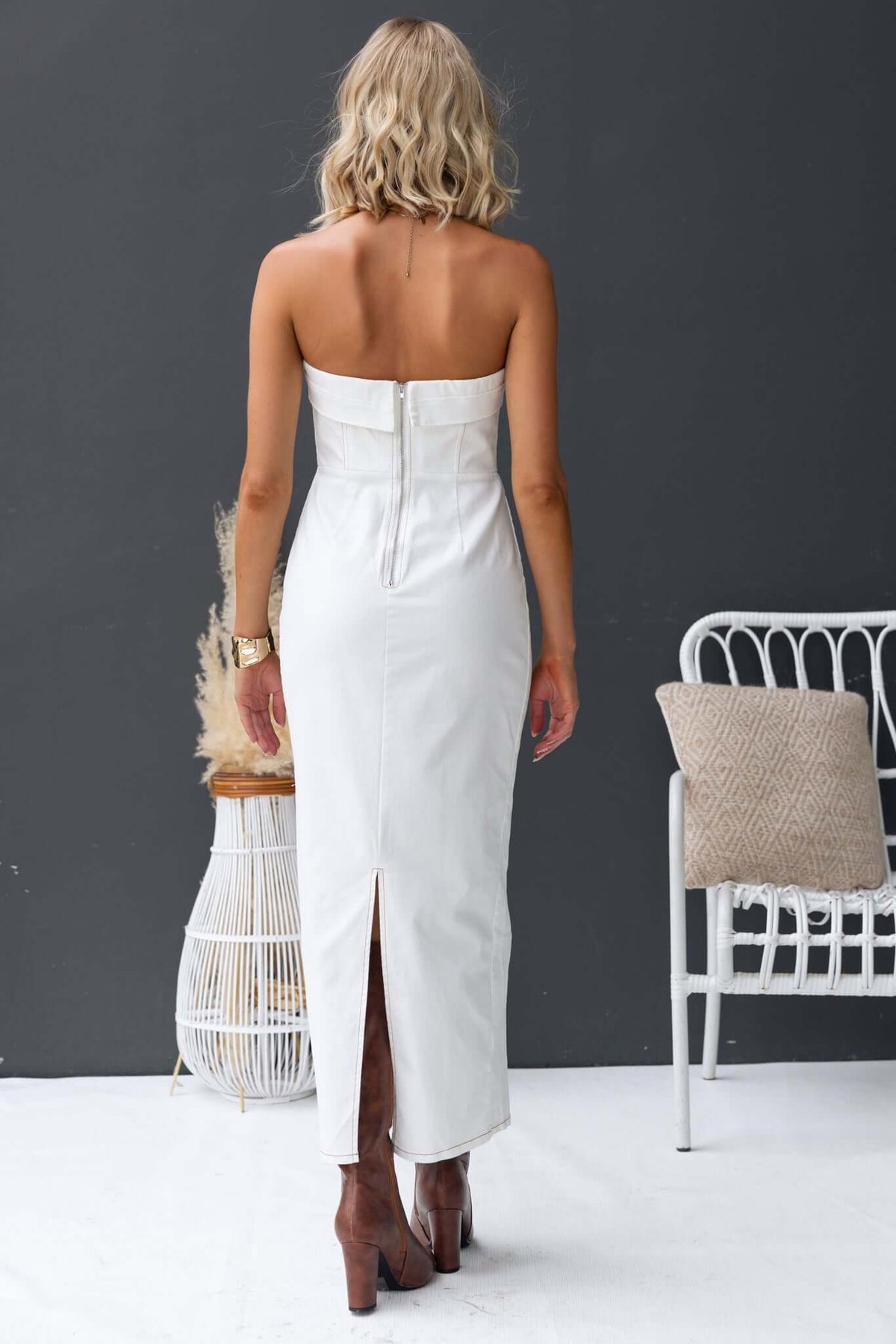 Back view of a strapless white denim maxi dress featuring a split and zipper, perfect for stylish outings.