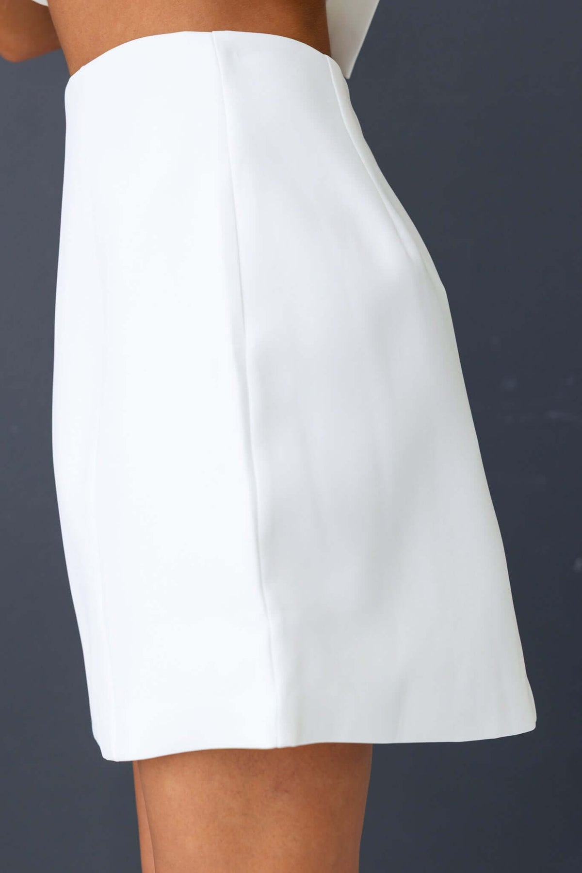 Laredo Skirt in white showcasing mid-high waist fit and invisible back zip, made of 100% polyester, dry clean only.