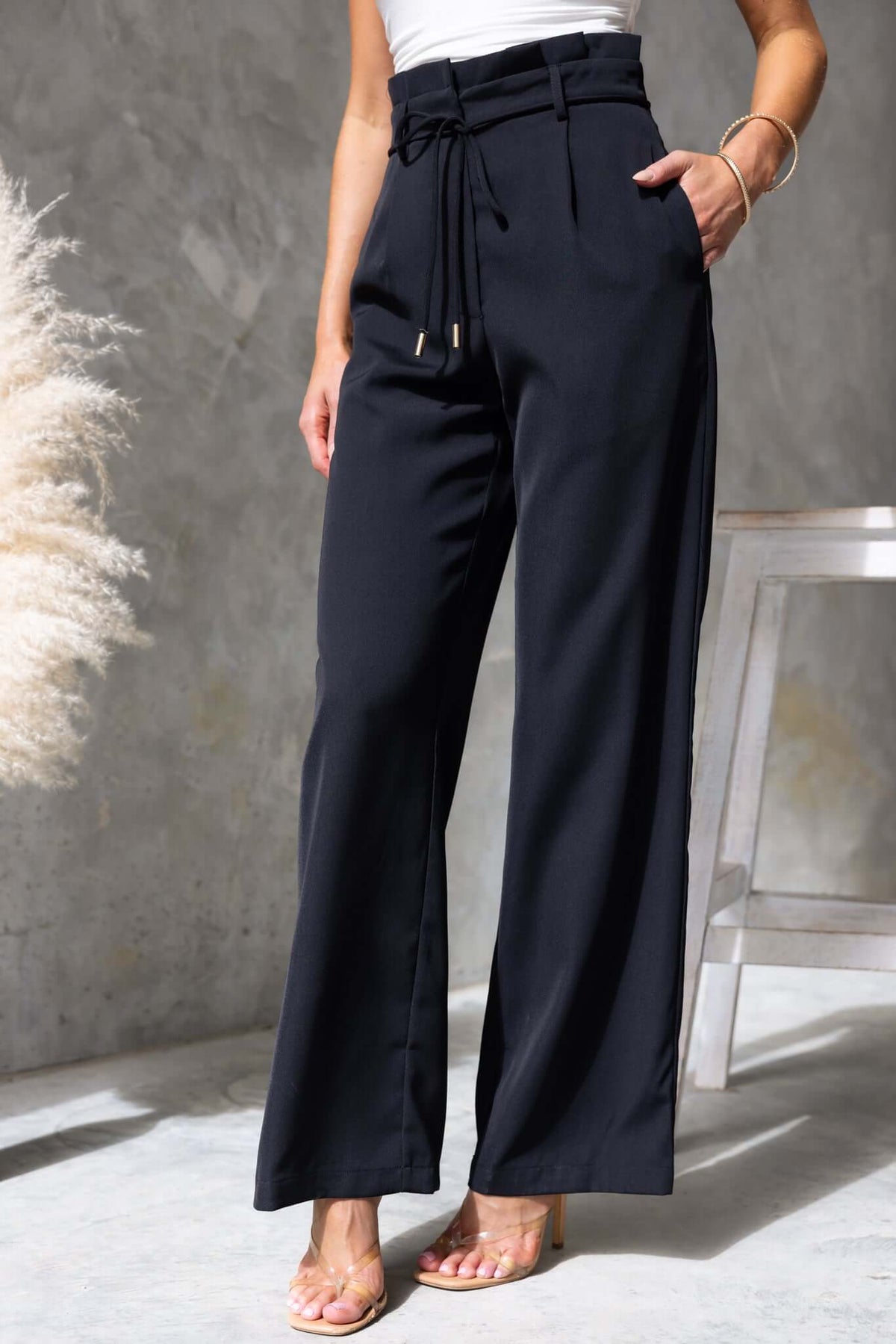 Lesky Pants featuring a paperbag waist, removable tie, pockets, and tailored fit, displayed in elegant black.