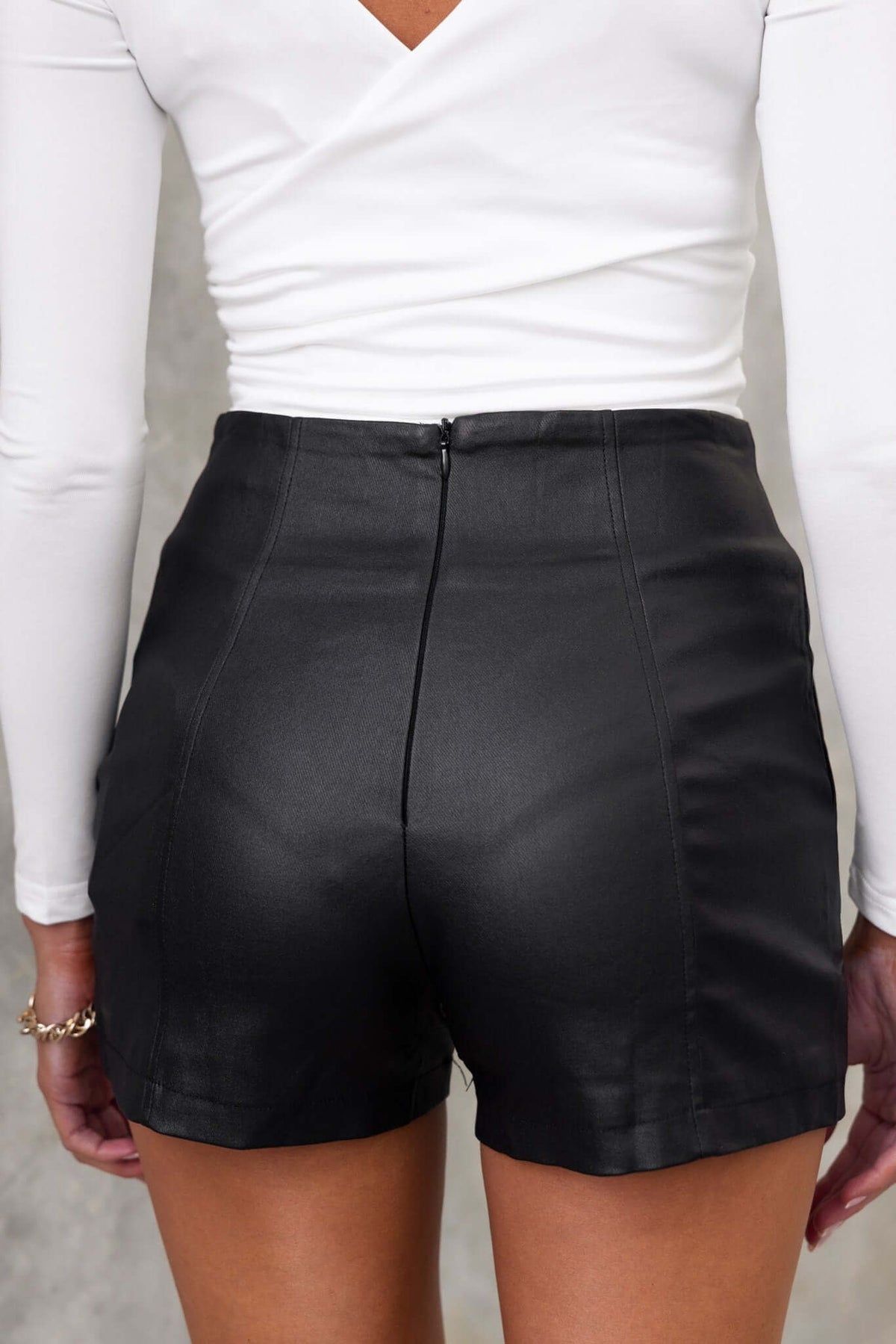 Back view of black Levin shorts with mid-high waist, invisible zip, and faux leather material.