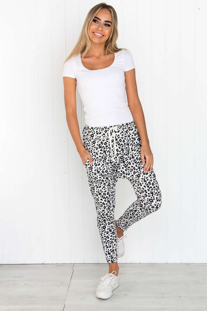 Model wearing a white scoop neck top with cap sleeves and leopard print jogger pants, showcasing a casual outfit.