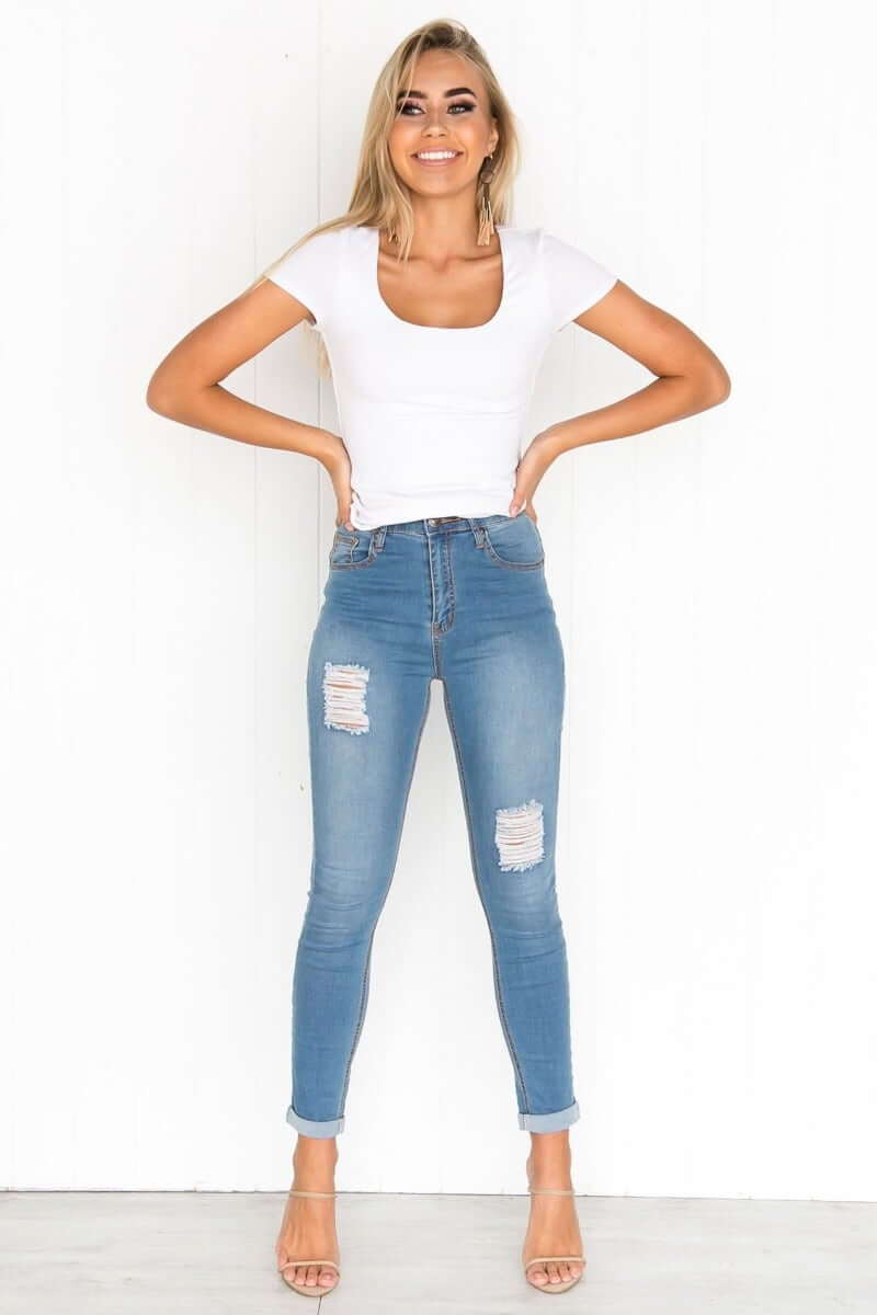 Model wearing Millie Top with scoop neckline and cap sleeves, paired with distressed jeans.