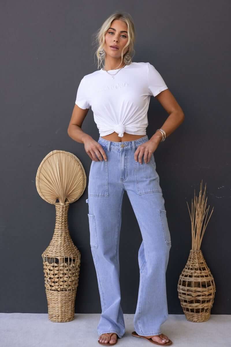 Woman wearing Madrid Jeans, a cargo style denim with mid-high waist fit, styled with a white knotted tee.