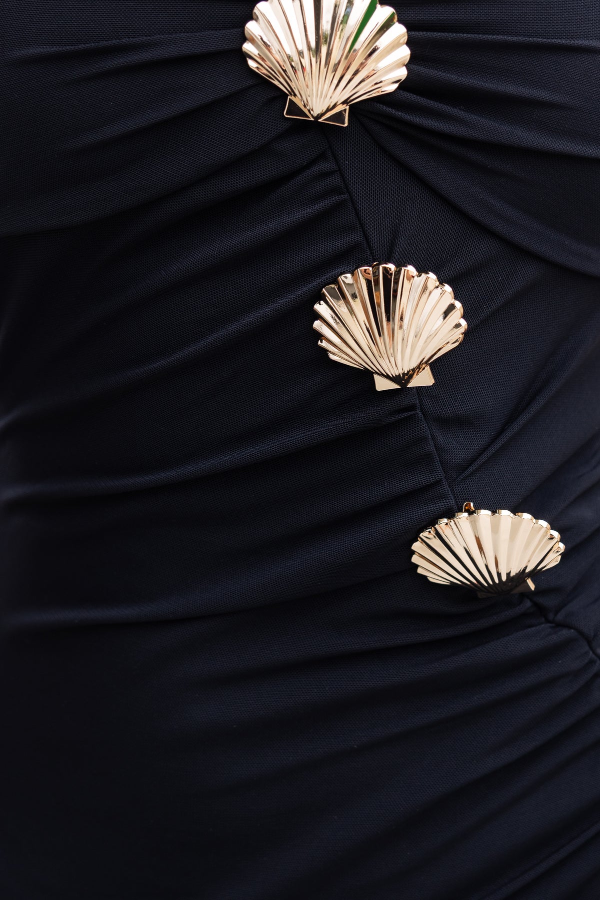 Close-up of Maloja Maxi Dress showing gold shell brooches on mesh fabric.