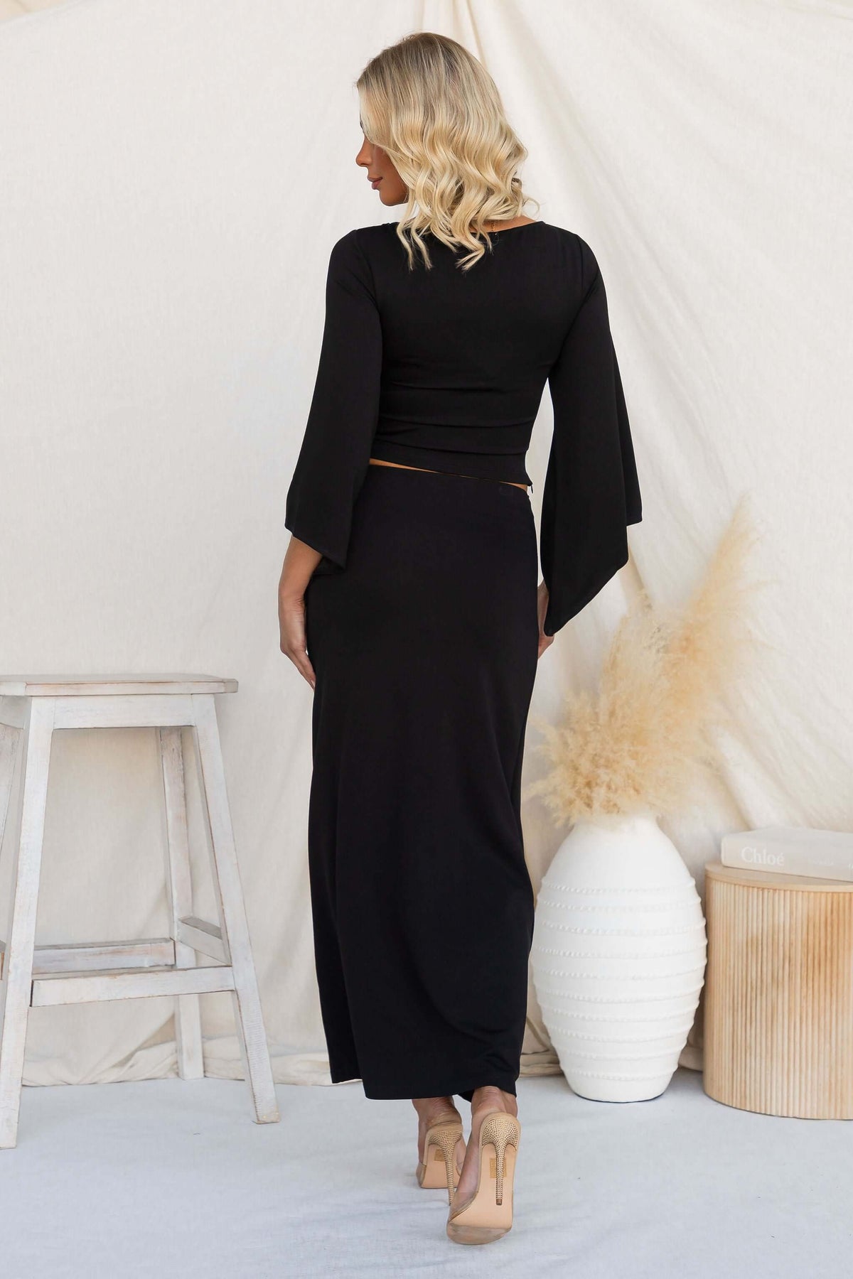 Back view of a model wearing the Maria Set, featuring cape sleeves and a maxi skirt.