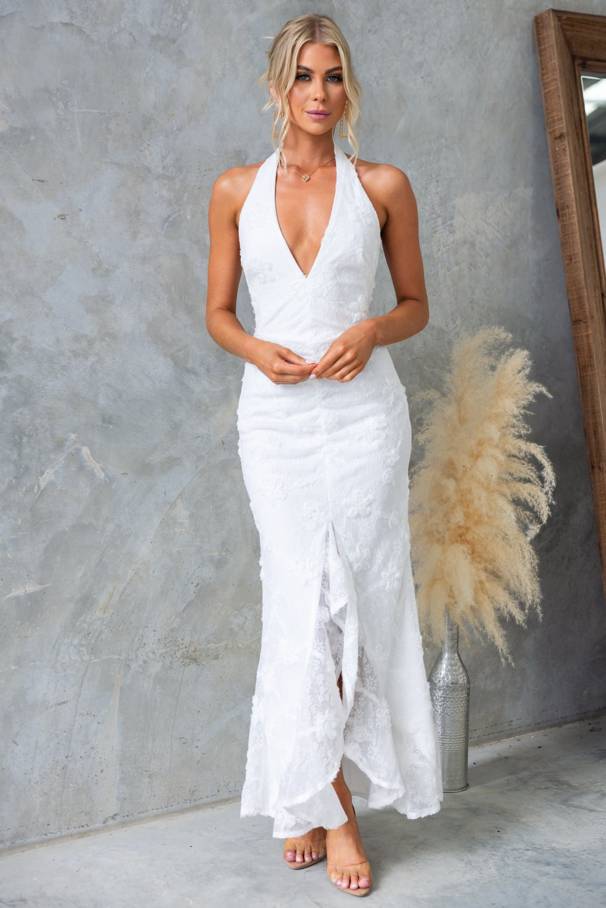 Model wearing Metrick Maxi Dress with halter V-neckline and fishtail hem, showcasing textured white fabric and elegant style.