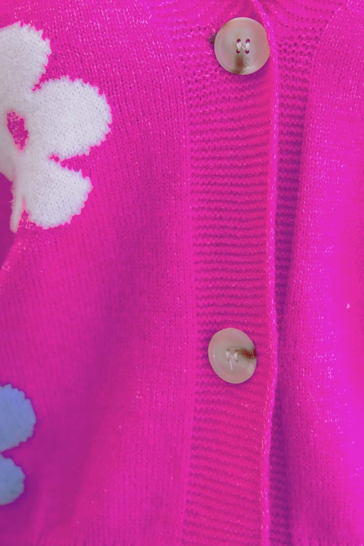 Close-up of Mimsie Cardigan featuring a V-neckline, button-up front, and floral design in pink and blue knit material.