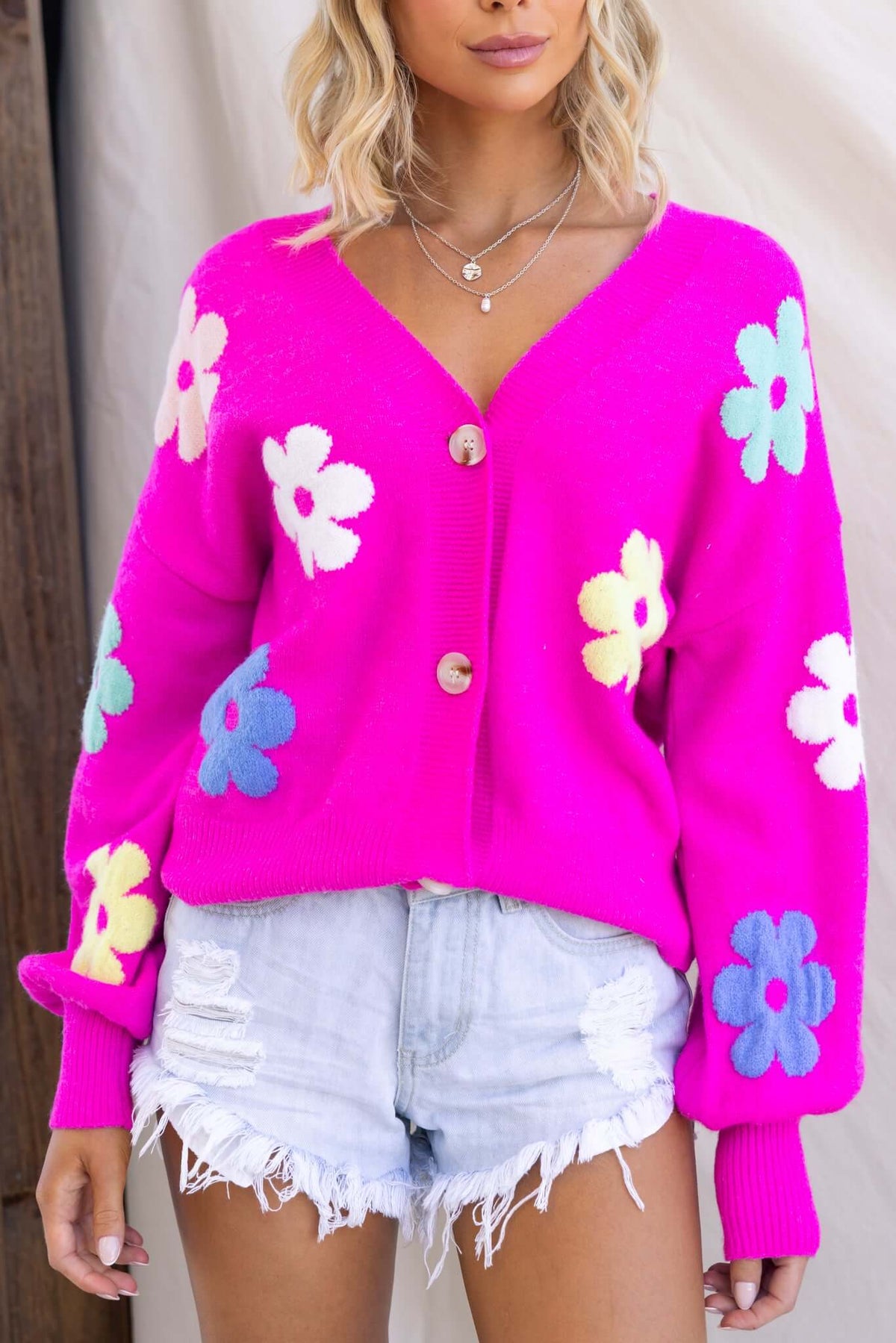 Mimsie Cardigan in bright pink with colorful floral patterns and V-neckline, styled with denim shorts.