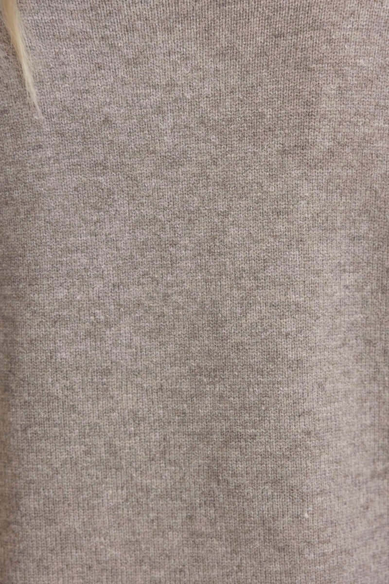 Close-up of a soft, light brown knitted fabric of the Motherly Cardigan, showcasing its ribbed texture.