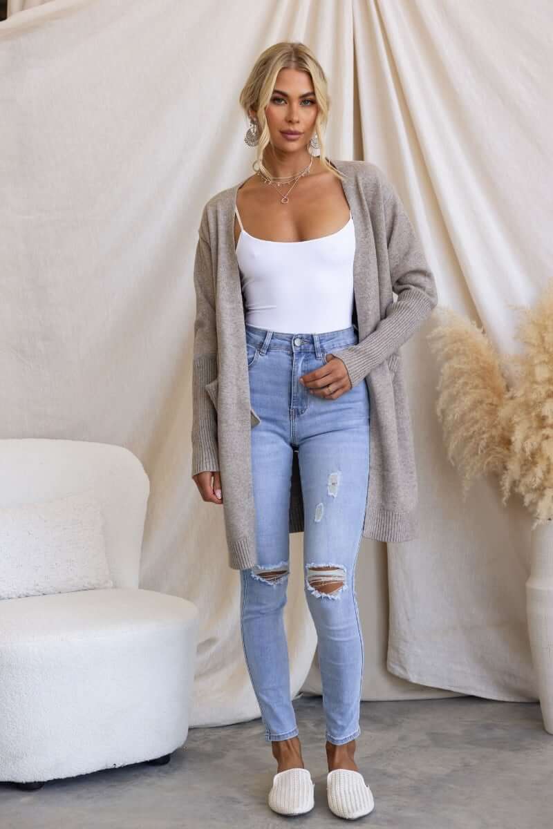 Stylish woman wearing a Motherly cardigan over a white top and distressed jeans, showcasing a casual look.