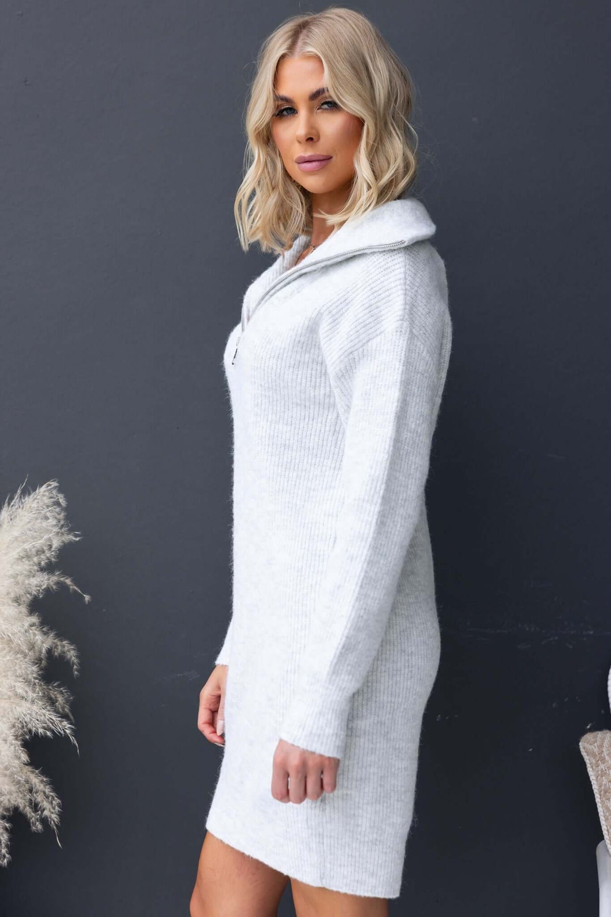 Model wearing Nayeli Dress, a light gray knit dress with 1/4 zip collar and ribbed material for relaxed fit.