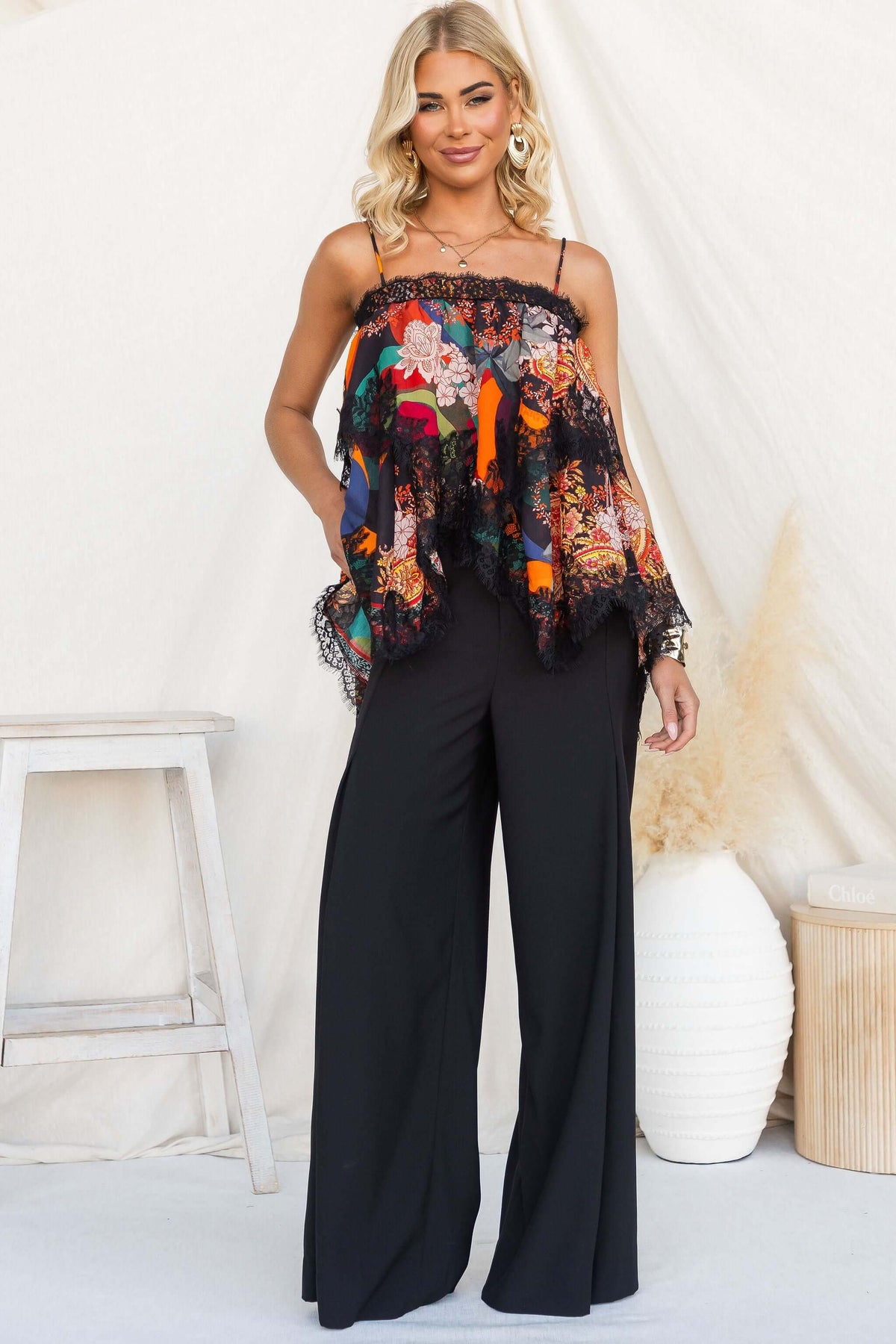 Nightingale Top featuring adjustable tie straps, square neckline, and lace detail styled with wide-leg black pants.