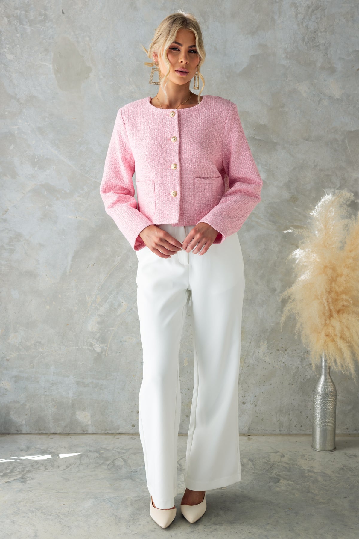 Noelle Jacket in pink chenille fabric, featuring button-up front, shoulder pads, and stylish pockets, worn with white trousers.