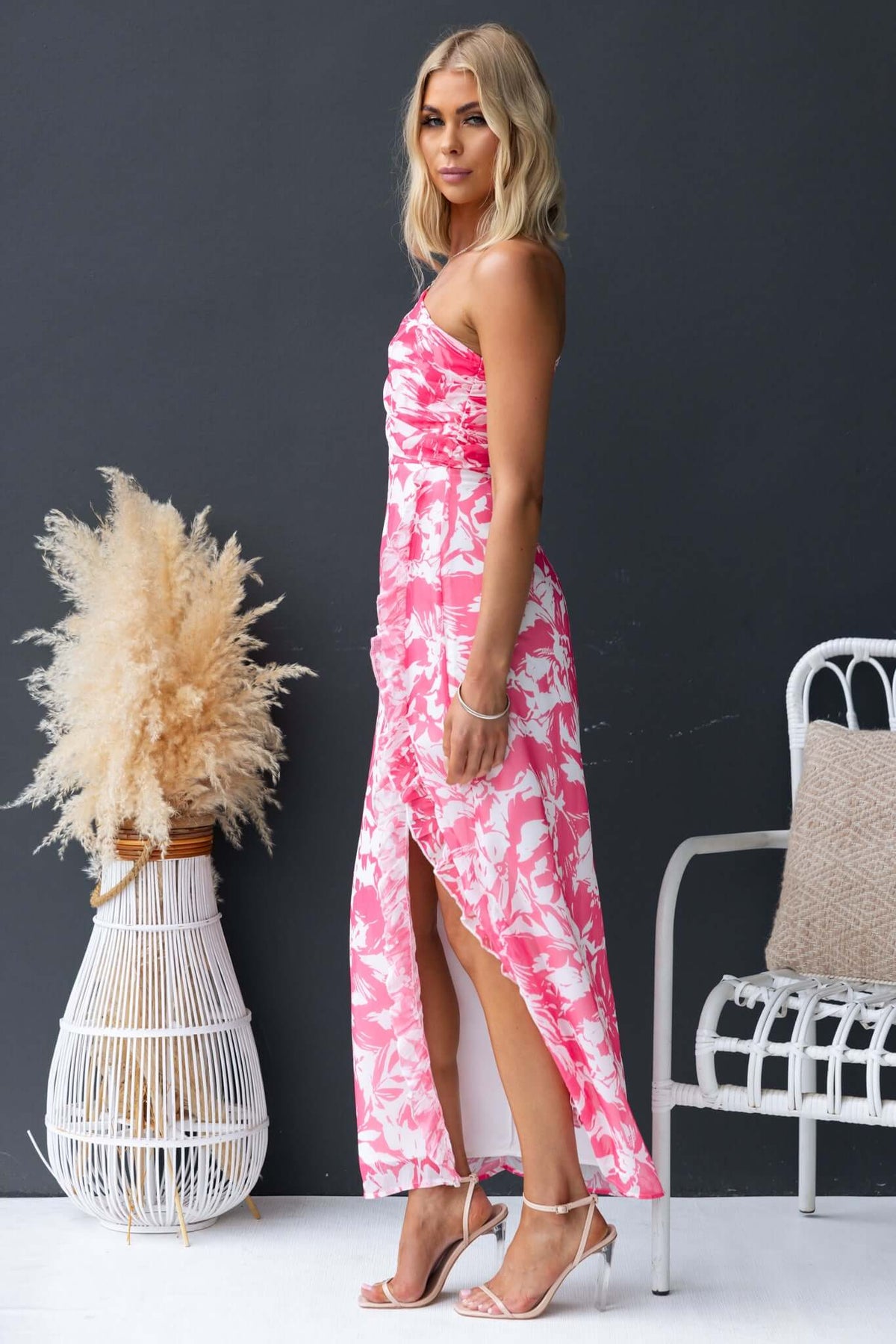 Model wearing Nurture Maxi Dress in pink floral pattern, featuring a side split and strapless design.