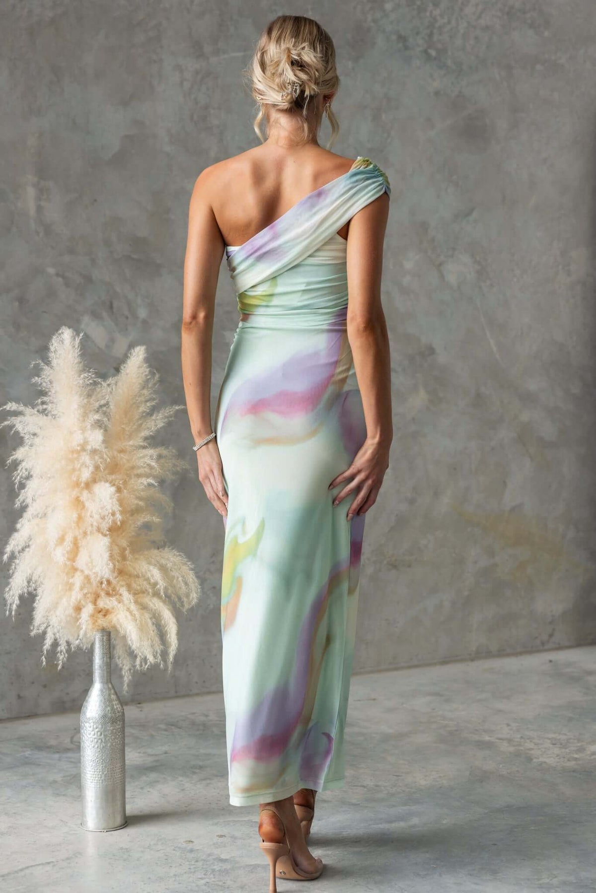 Model wearing Otelia Maxi Dress with one-shoulder neckline and colorful mesh fabric, showcasing the back view in a studio setting.