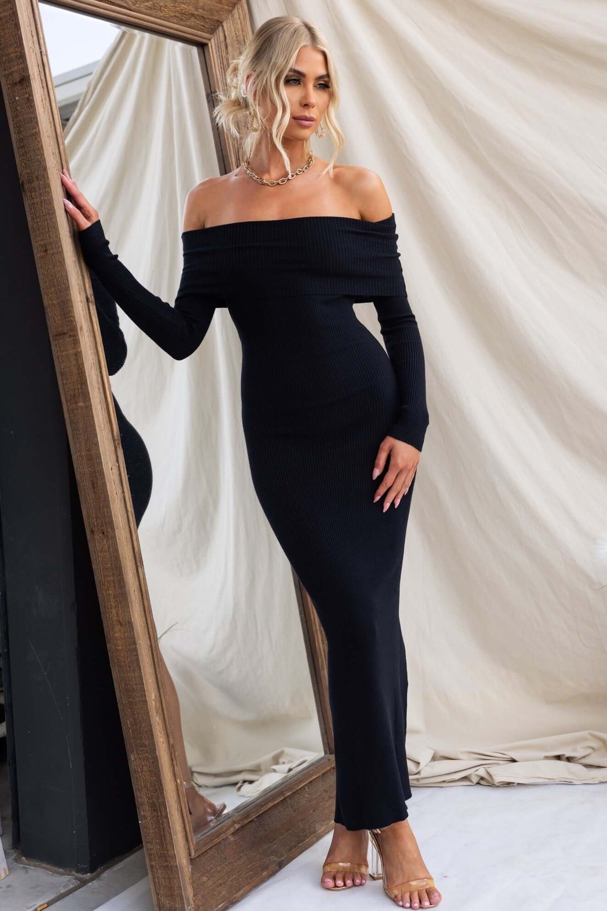 Model wearing an Oxnard Maxi Dress in ribbed knit, off-shoulder neckline, and back split, styled with a mirror backdrop.