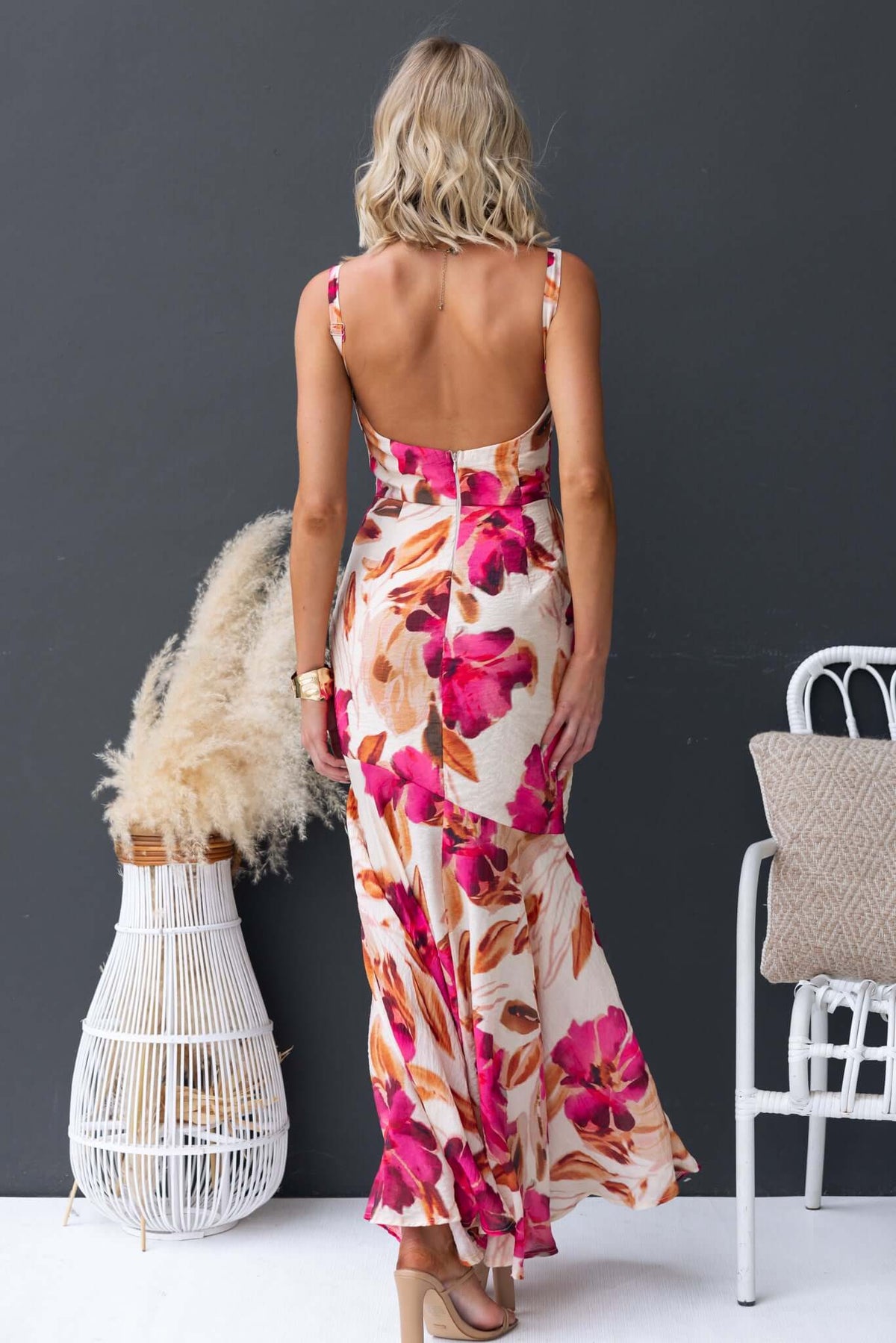 Back view of a model in an Ozias Maxi Dress with floral print, featuring adjustable straps and a flowing chiffon design.
