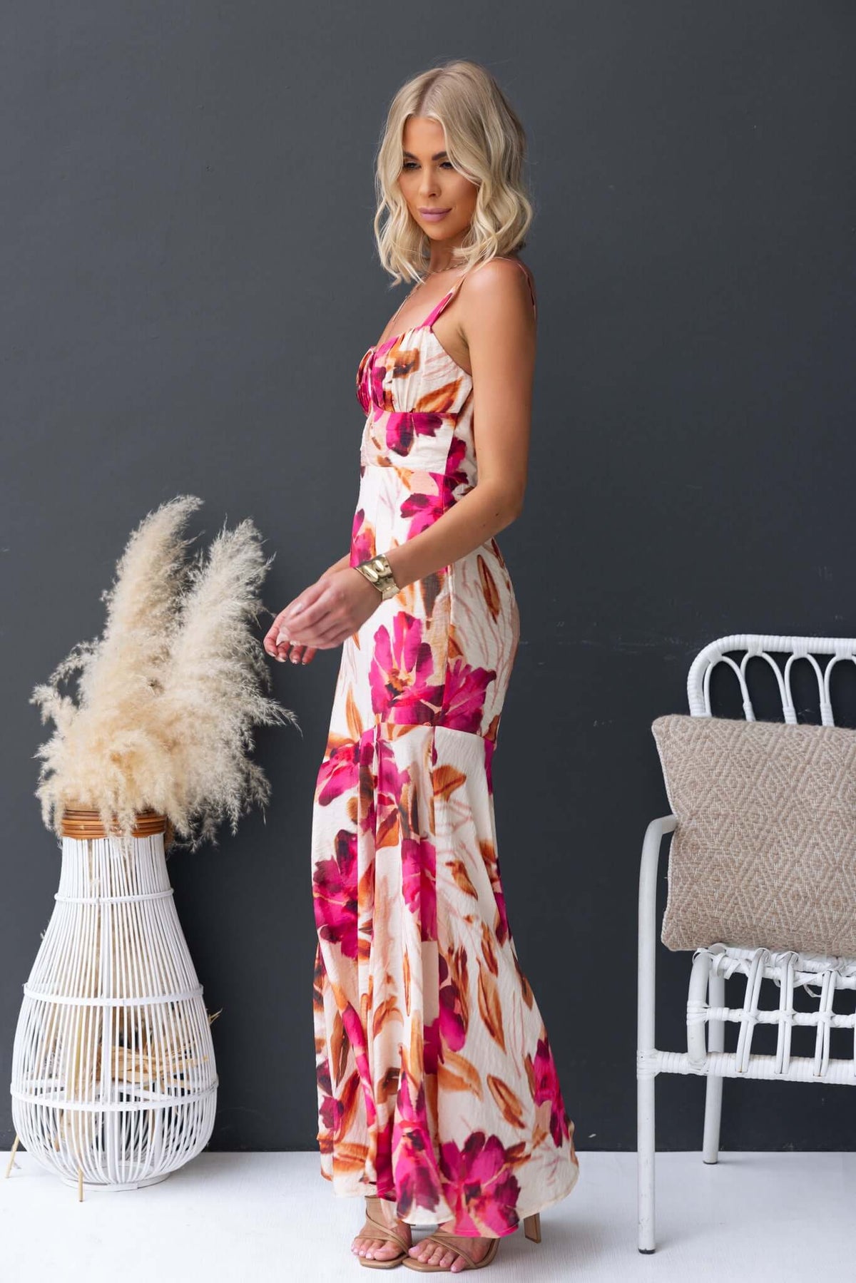 Model wearing Ozias Maxi Dress with floral design, adjustable straps, and front split, styled against a modern backdrop.