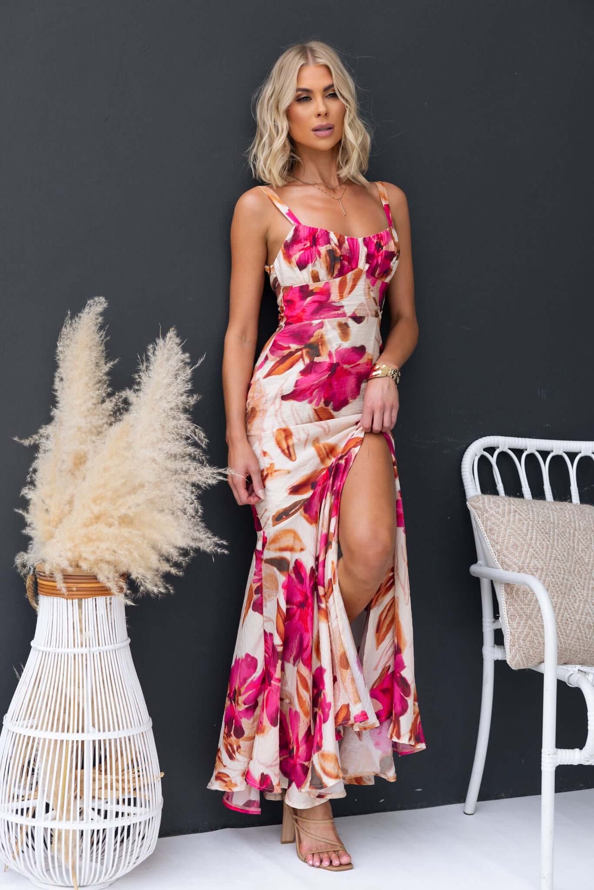 Model wearing Ozias Maxi Dress with floral print and a front split, showcasing adjustable straps and chiffon material.