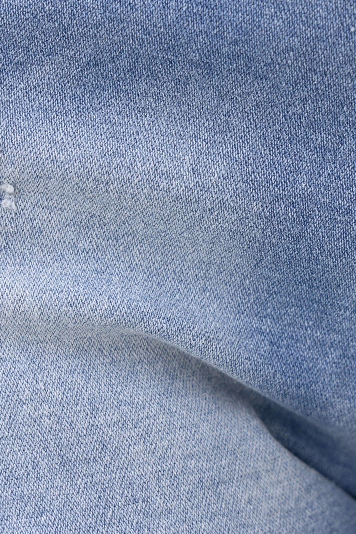 Close-up of light blue denim texture showing distressed detailing for Pecos Denim Shorts.