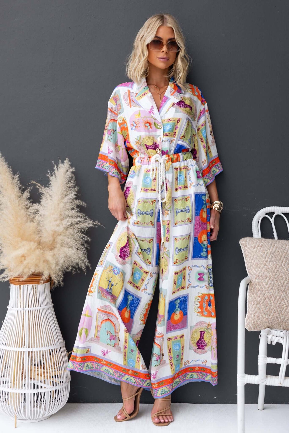 Perrin jumpsuit featuring a colorful print, collar, button-up front, and elastic waistband with pockets.