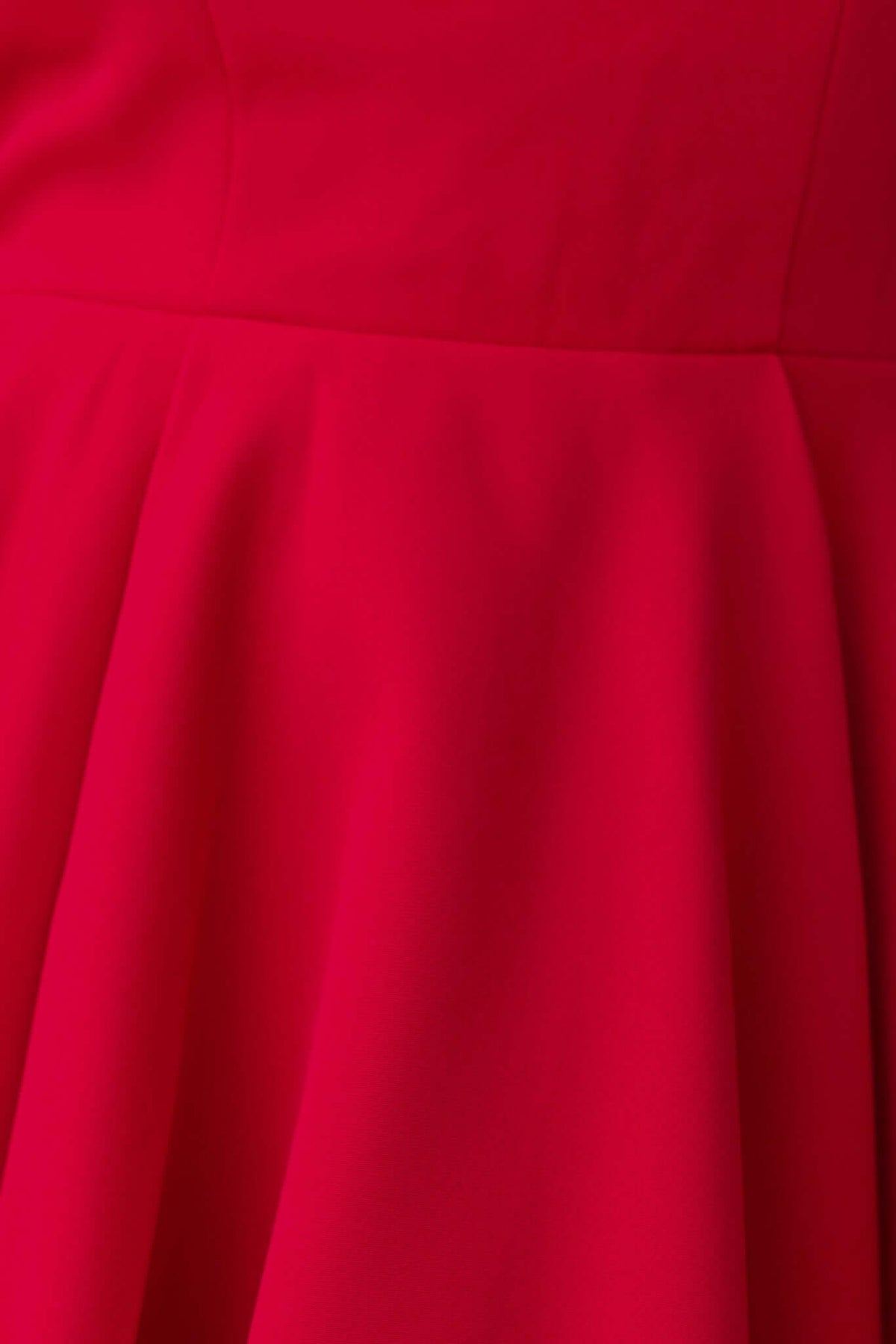 Close-up of the vibrant red fabric of the Pescia Dress, featuring a smooth finish and pleated skirt design.