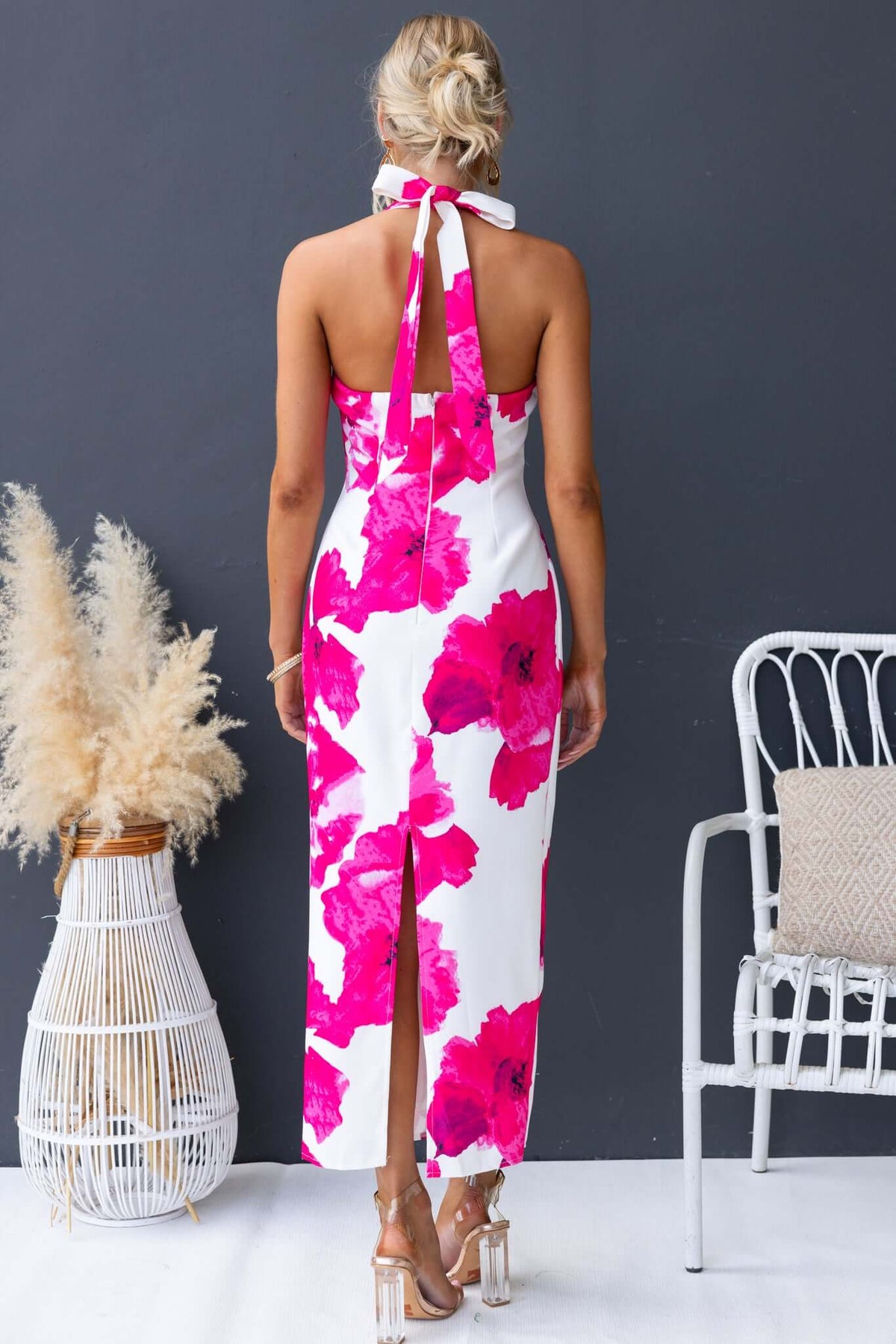 Back view of Pianni Maxi Dress featuring tie halter neckline, floral print, and split at the back, styled with minimal accessories.