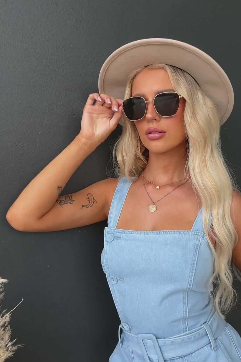 Model wearing Zaza Denim Playsuit with button-up front, adjustable straps, and sun hat, showcasing a casual summer style.