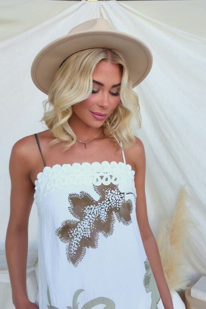Woman wearing Carlo Maxi Dress with floral design and wide-brimmed hat, styled for summer fashion.