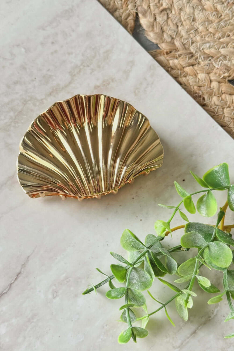 Azure claw clip with metallic finish, 10cm in length, displayed on a marble surface with greenery.