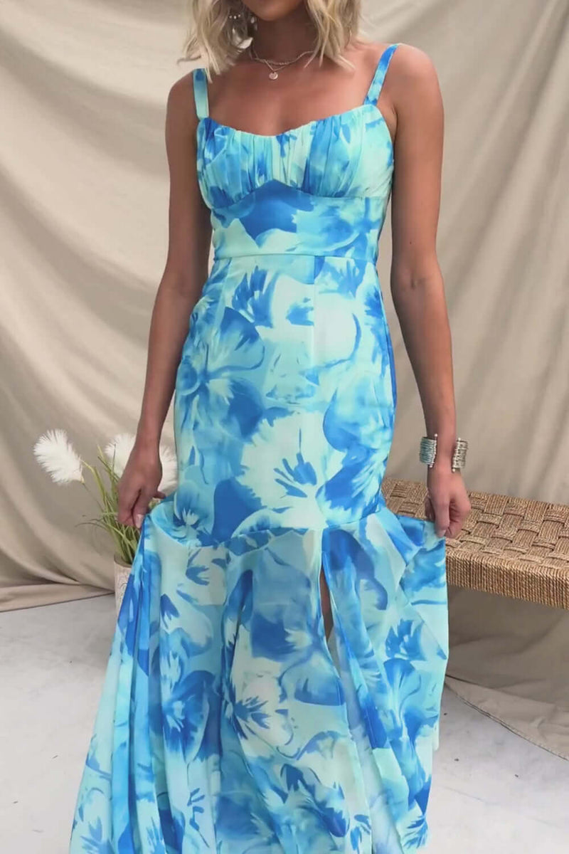 Model wearing the Ozias Maxi Dress featuring a blue floral chiffon design, adjustable straps, and front split.