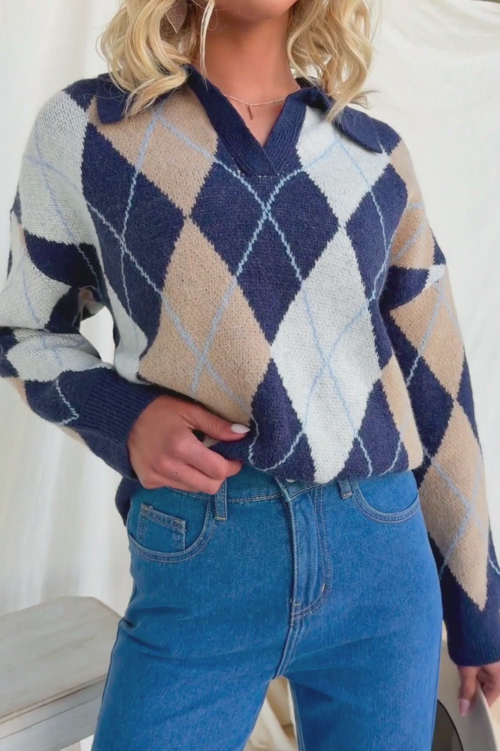 Model wearing Vella Jumper, a navy based knit jumper with collar and argyle pattern, paired with jeans.