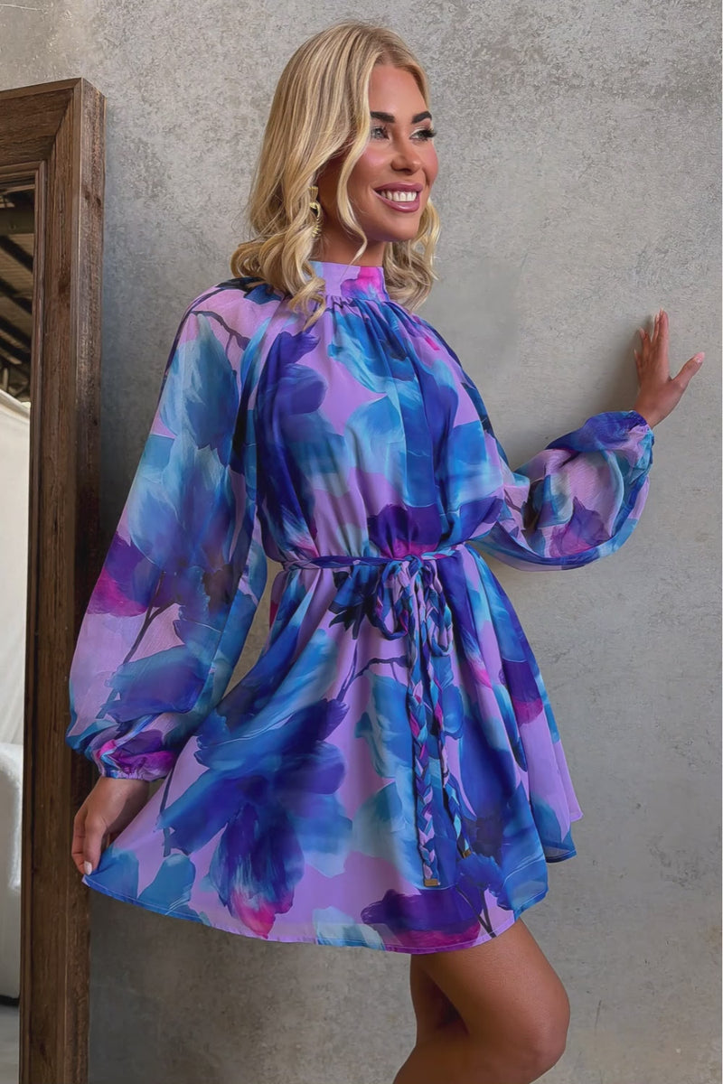 Model wearing a vibrant Siletto Dress with floral patterns and tie detail, showcasing the elegant design.