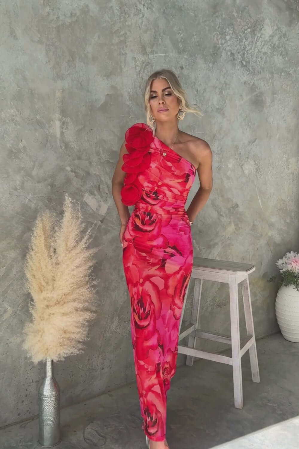 Model wearing Meriden Maxi Dress with one-shoulder neckline and floral print, featuring a pink and red color palette.