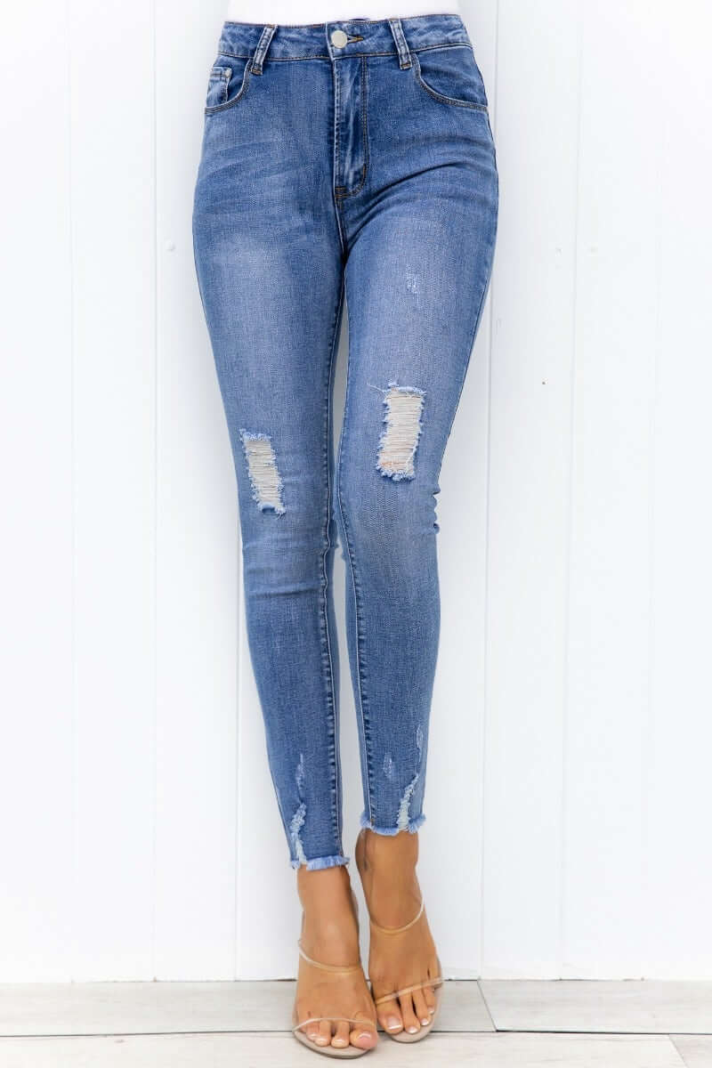 Qilli Jeans featuring distressed rips, raw hem, and a flattering fit, perfect for casual wear.