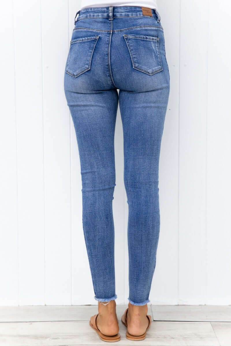 Back view of Qilli Jeans featuring distressed details and raw hem in light blue denim.