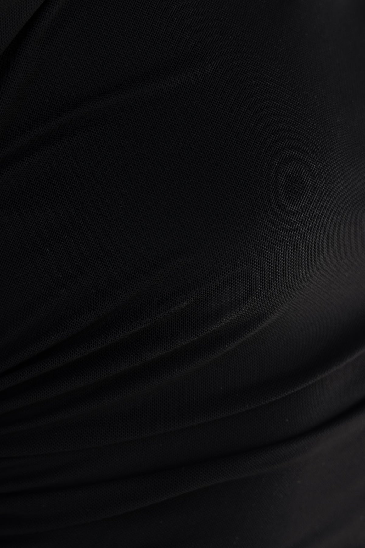 Close-up of Queta Maxi Dress fabric with a smooth black texture and subtle ruched detailing.